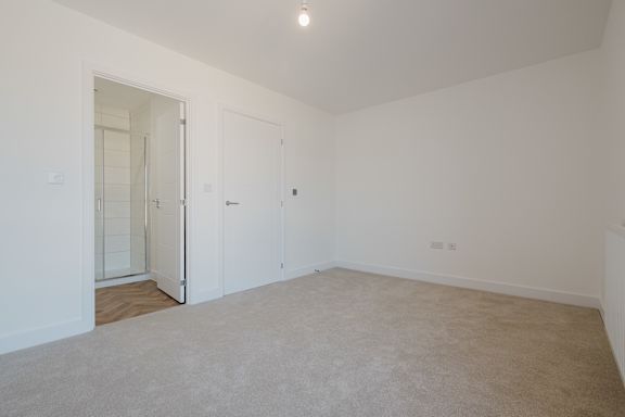 A room with a carpeted floor and a doorway leading to another room.