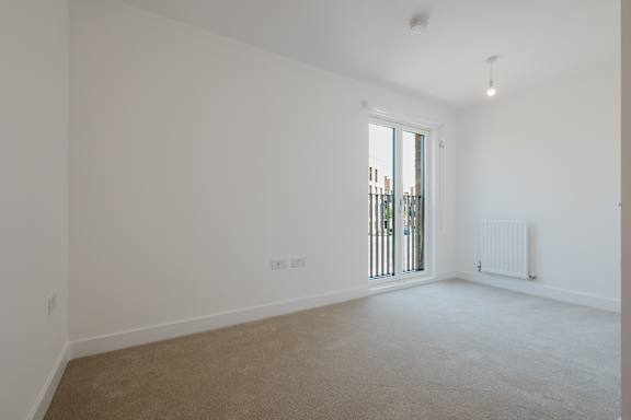 A room with a carpeted floor and a window with a view of a fence.