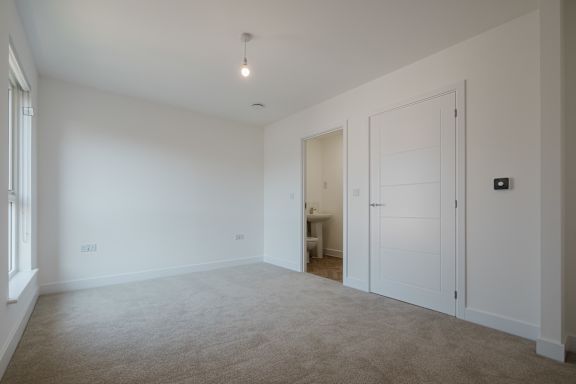 A large, empty room with a carpeted floor and white walls.