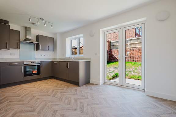 A kitchen with a herringbone patterned floor and a large window.