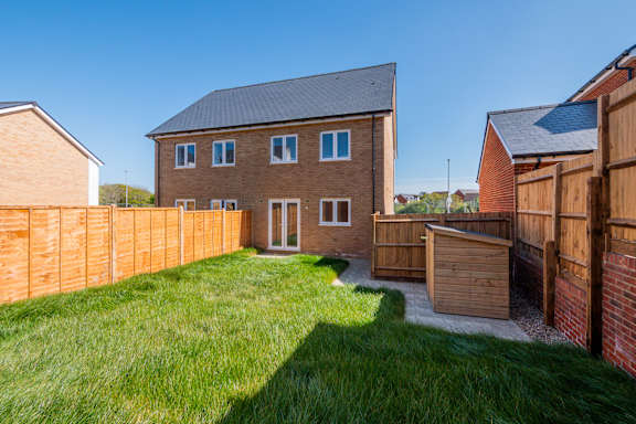 A house with a brown fence and a green lawn.