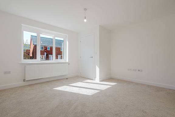 A room with white walls and a window overlooking a red building.