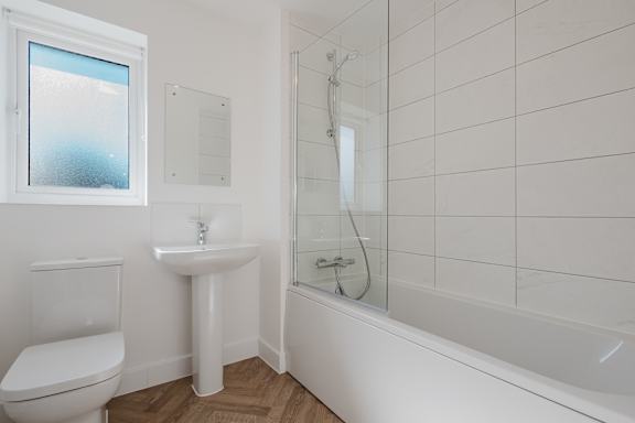 A white bathroom with a toilet, sink, and bathtub.