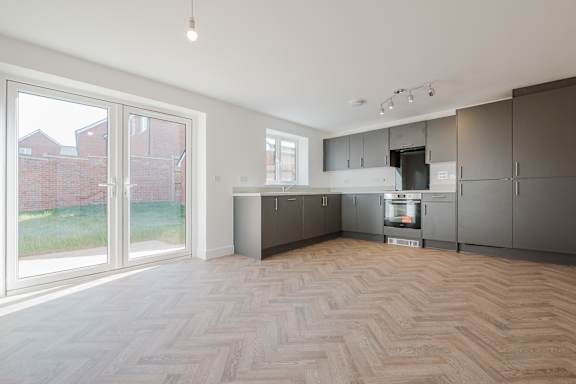 A kitchen with wooden flooring and grey cabinets.