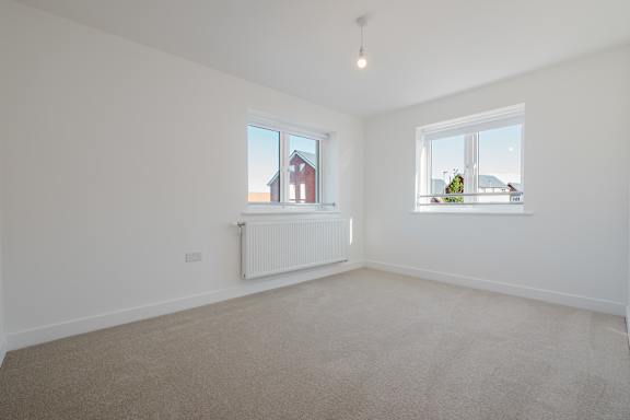 A room with a carpeted floor and two windows.