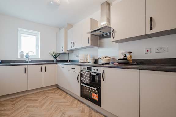 A kitchen with a white oven and wooden flooring.