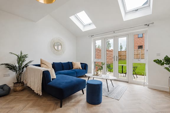 A blue couch with a white throw blanket on it in a room with a skylight.