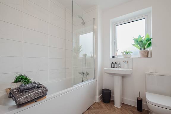 A white bathroom with a tub, sink, and window.