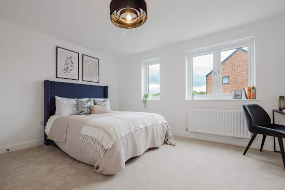 A bedroom with a bed, chair, and pictures on the wall.
