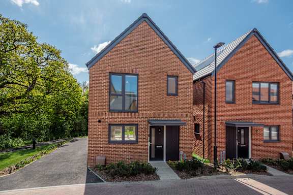 A red brick house with a driveway in front.