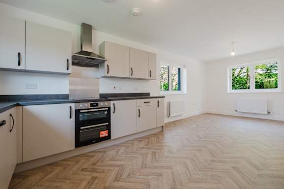 A kitchen with wooden flooring and white cabinets.