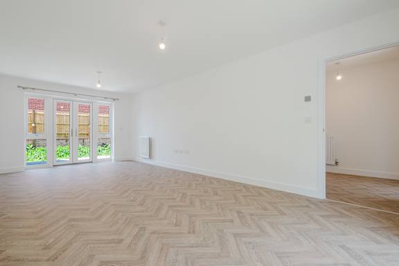 A room with a herringbone patterned floor and a window with a view of a garden.