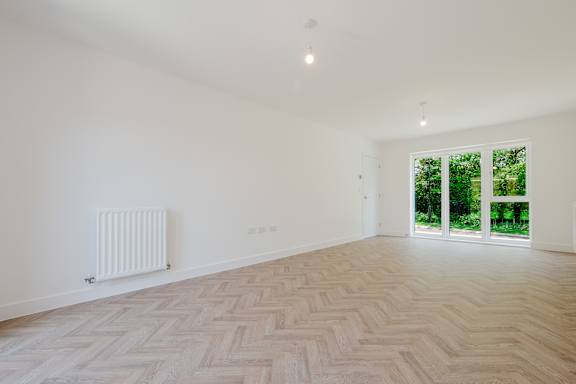 A room with a herringbone patterned floor and a sliding glass door.