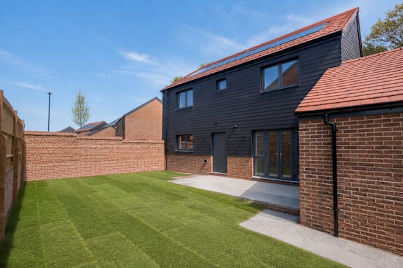A modern house with a black exterior and a red roof.