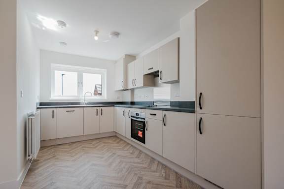 A kitchen with white cabinets and a black countertop.