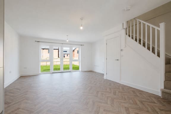 A spacious room with a staircase and a large window with a view of the outside.
