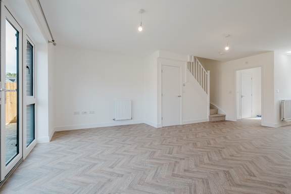 A spacious room with a wooden floor and white walls.