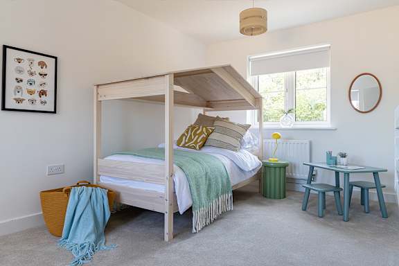 A bedroom with a four poster bed and a table with chairs.