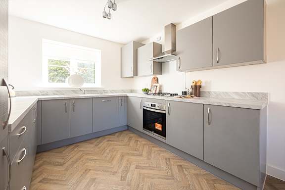 A kitchen with grey cabinets and a wooden floor.