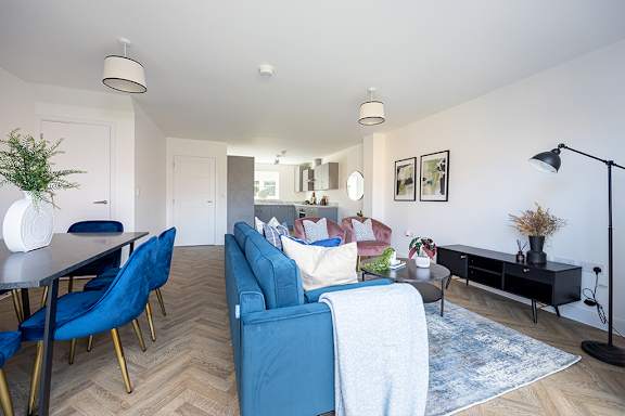A living room with a blue couch and a dining table with blue chairs.