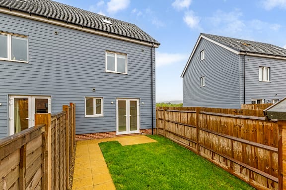 A blue house with a wooden fence and a green lawn.