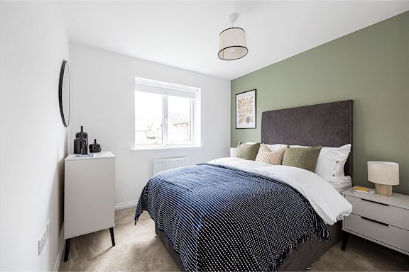 A bedroom with a bed, nightstand, and window.