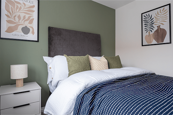 A bed with a white comforter and a blue striped blanket.