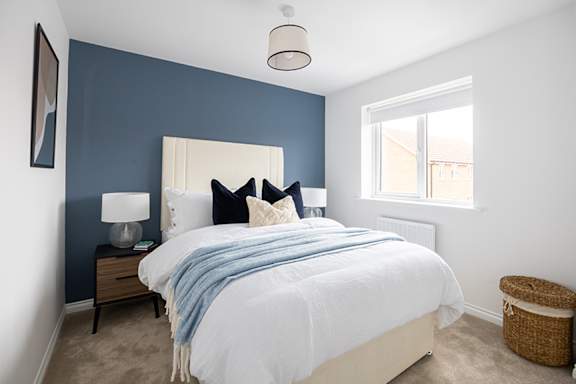 A bedroom with a white bed and a blue blanket.