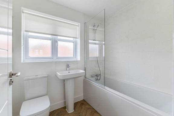 A white bathroom with a toilet, sink, and bathtub.