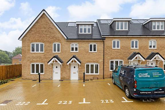A blue van is parked in a parking lot in front of a brick building.