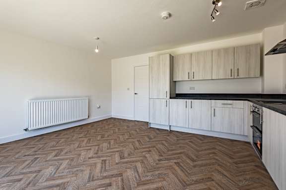A kitchen with white cabinets and a wooden floor.
