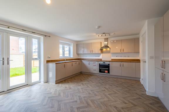 A kitchen with a white ceiling and wooden flooring.