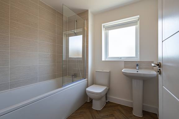 A white bathroom with a toilet, sink, and bathtub.