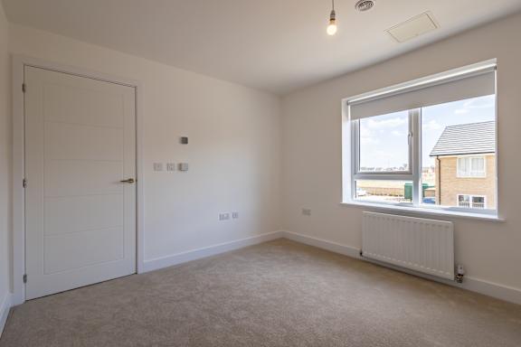A room with a white door, a window, and a radiator.