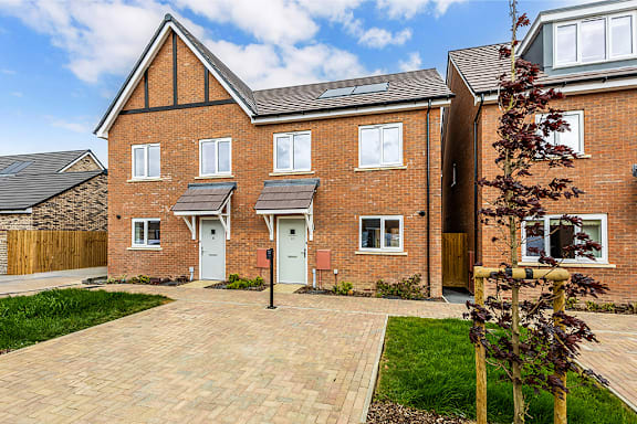 A red brick house with a grey door and windows.