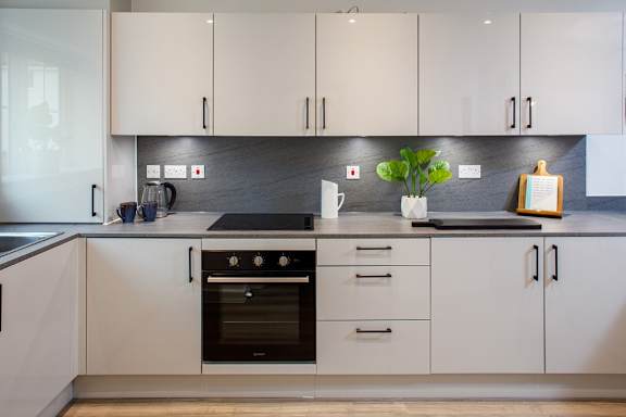 A modern kitchen with white cabinets and a black stove top.
