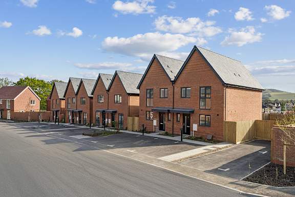 A row of red brick houses with a clear blue sky above.