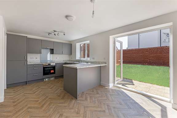 A kitchen with a marble countertop and a herringbone patterned floor.
