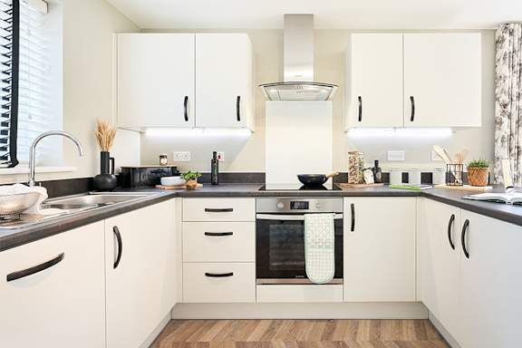 A modern kitchen with white cabinets and a black countertop.