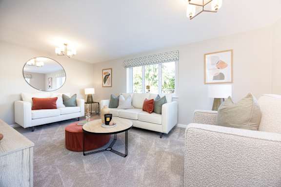 A living room with white furniture and a round mirror on the wall.