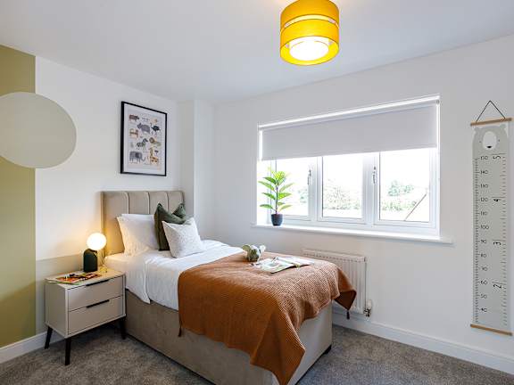 A bedroom with a bed, nightstand, window, and a plant.