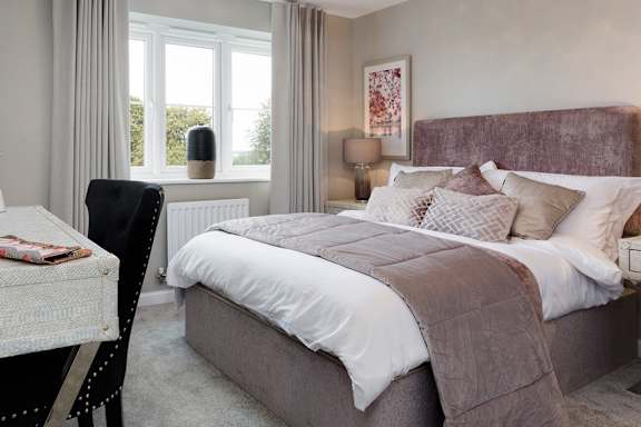A bedroom with a large bed and a window with curtains.