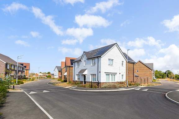 A residential street with houses on both sides and a clear sky.
