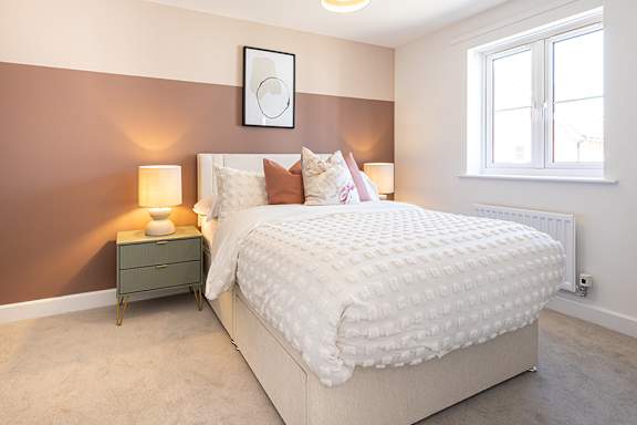 A bedroom with a large bed and a nightstand with a lamp.