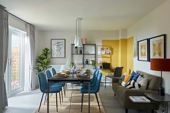 A dining room with a table set for six and a couch with a pillow on it.