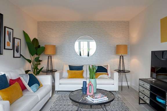 A living room with a white couch, a coffee table, and a large mirror on the wall.