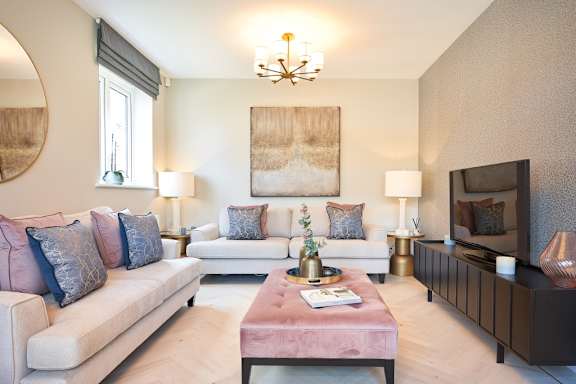 A living room with a white couch, a pink table, and a chandelier.