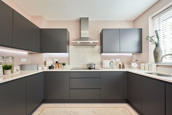 A kitchen with black cabinets and a wooden floor.