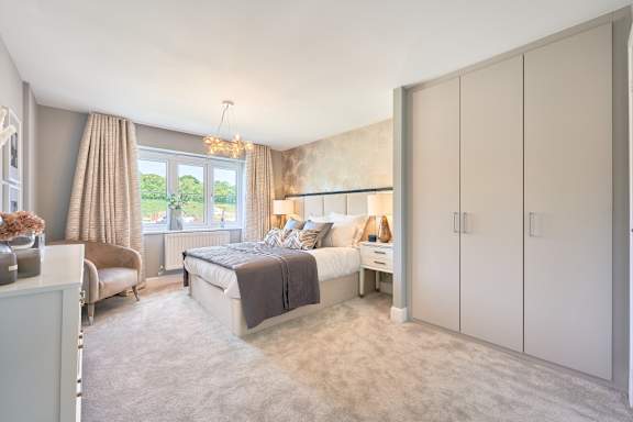 A bedroom with a large bed and a window with curtains.