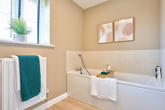 A bathroom with a white bathtub and a green towel hanging on the radiator.